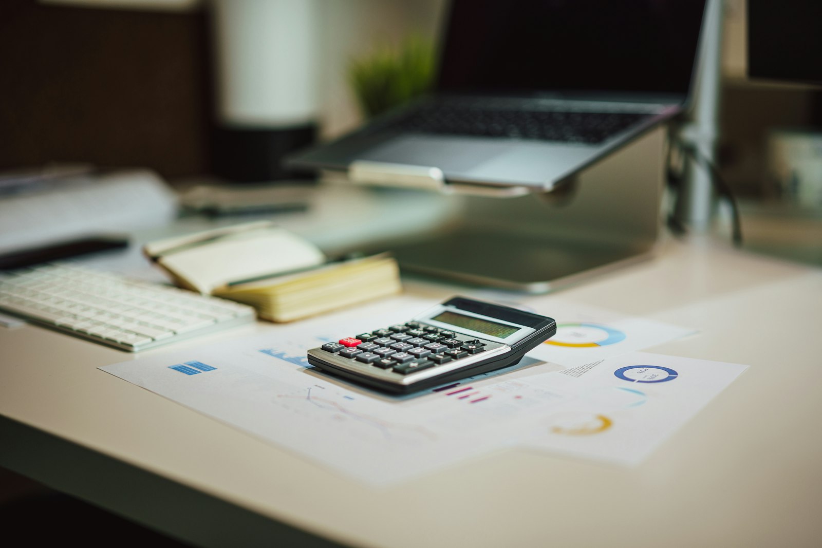 A calculator on a desk next to a laptop, working through the numbers on a payoff plan